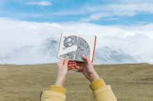 Crop Hands Holding Picture Book On Mountainscape