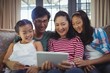 © WavebreakMediaMicro - Smiling family using digital tablet together in living room