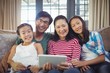 © WavebreakMediaMicro - Smiling family using digital tablet together in living room