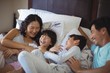 © wavebreak3 - Happy family having fun on bed in the bed room