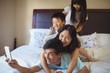 © wavebreak3 - Happy family taking a selfie on mobile phone in the bed room