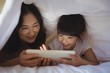 © wavebreak3 - Mother and daughter using tablet under blanket