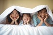© wavebreak3 - Family relaxing together under a blanket in bedroom
