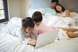© wavebreak3 - Sibling using laptop in bedroom