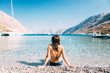 © Micky Wiswedel/Stocksy - woman in a bikini sitting on an idyllic beach in Greece