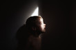 © Julia Forsman/Stocksy - Profile of young boy in small batch of light in dark room