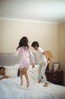 © wavebreak3 - Siblings jumping on bed in bedroom