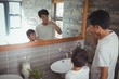 © wavebreak3 - Father and son brushing teeth together in bathroom