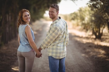 Wall Mural - Young couple holding hands while walking 