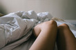 © Jacqui Miller/Stocksy - Woman's legs in bed