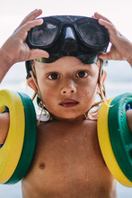 Portrait Of A Wet Toddler With Diving Goggles On The Head And Swimming Rings