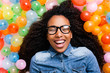 © BONNINSTUDIO/Stocksy - Young african woman playing with many colorful balloons