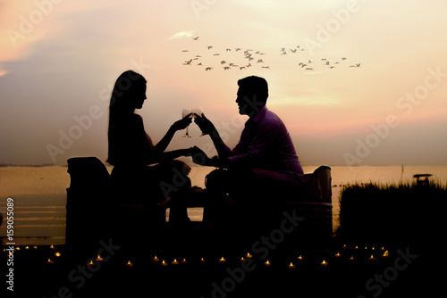 silhouette romantic couple enjoying glass of wine in a beautiful sunset ...