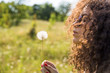 © Jovo Jovanovic/Stocksy - Young woman blowing mature dandelion flower