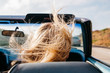 © Jesse Morrow/Stocksy - Young blonde female hair blowing in wind while riding in convertible car