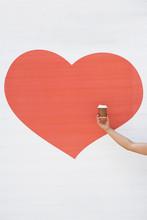 Woman's Hand Holding A Coffee Cup Against A Heart Shaped Background