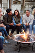 © Trinette Reed/Stocksy - Group of friends and family relaxing around a fire pit at a farm