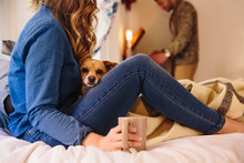 Young Couple Relaxing In Bedroom With Dog