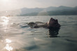 © michela ravasio/Stocksy - Young woman floating in lake at sunset