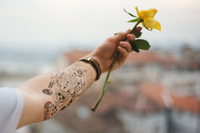 Tattooed Hand Holding A Yellow Rose