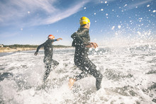 Two Triathletes Running To The Water On Triathlon Race Splashing Water