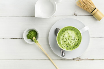 Matcha latte cup on white background top view. This latte is a delicious way to enjoy the energy boost & healthy benefits of matcha. Matcha is a powder of green tea leaves packed with antioxidants.