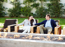 Couple Relaxing At Outdoor Lounge Fire Pit With Wine 