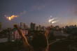 © Jovo Jovanovic/Stocksy - Girl on a rooftop holding sparkle sticks during the twilight hours of the city