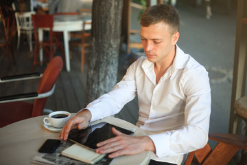 Young man using digital tablet computer in street cafe.