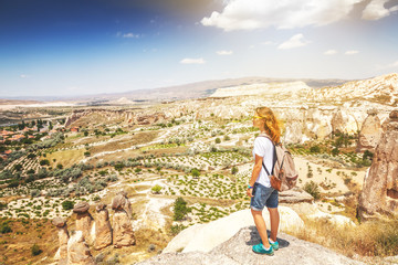 Wall Mural - A young woman traveler stands on a mountain and admires the view. Turkey, Cappadocia