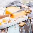 Delicious dutch gouda cheese with cheese blocks, crackers, walnuts and special knife on oud wooden table. Copy space.