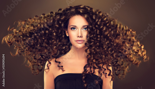 Zdjęcie XXL Brunetka z długimi i błyszczącymi falującymi włosami. Piękny model z kręcone fryzury.