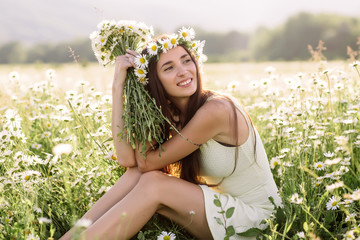 Beautiful woman enjoying daisy field, nice female lying down in meadow of flowers, pretty girl relaxing outdoor, having fun, holding plant, happy young lady and spring green nature, harmony concept