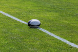 Rugby ball on green pitch and white line