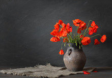 Still Life In A Rustic Style: An Old Crock And A Bouquet Of Red Poppies On A Wooden Table