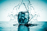 Fototapeta  - Creative splashing water in the glass with ice, sharp and clean, spot light
