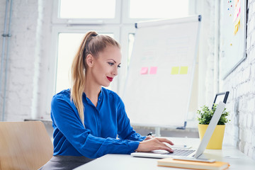 Wall Mural - Attractive woman working on laptop in start-up office