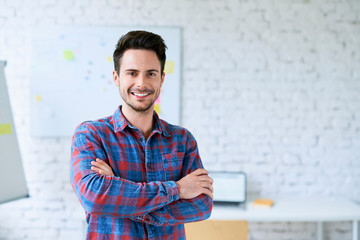 Portrait of successful programmer, web designer standing in start-up office