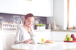 © lenets_tan - Young woman with orange juice and tablet in kitchen.