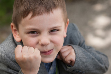 Small smiling boy threatens with fists taking boxing rack