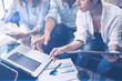 © SFIO CRACHO - Three young coworkers working on mobile laptop computer at office.Young woman holding tablet and pointing on touch screen. Horizontal, blurred background.