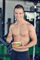 Powerful athletic man with great physique eating a healthy salad.