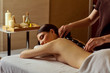 © Studio Romantic - Massage stones on back of a woman at the spa salon.