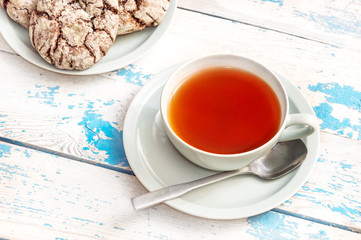 Cup of tea and saucer with cookies on the old table.