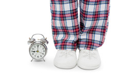Alarm Clock And Female Legs In Pajamas And Slippers On A White Background Closeup