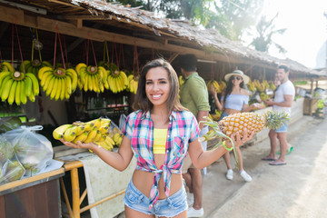 Wall Mural - Woman Hold Bananas And Pineapple On Street Traditional Market, Young Man And Woman Travelers Choosing Fresh Fruits