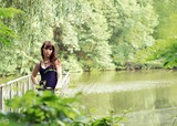 Fototapeta  - Beautiful woman in sundress on the pond bridge