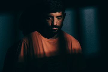 Prisoner man in dark cell illuminated only by a beam of light