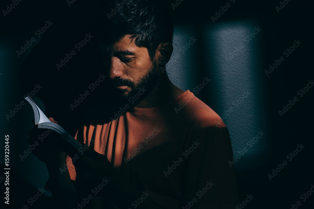 Read Books Men Lock In Prisoner man in dark cell reading a book or bible Stock Photo | Adobe Stock