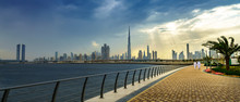 Panoramic View Of Business Bay, Downtown Area Of Dubai And Two Arab Men Take A Walk On The Promenade At Cloudy Day. UAE